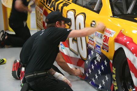 Custom work: Race team members apply a suitably patriotic new wrap to the #20 DeWalt NASCAR Toyota Camry in preparation for a July 4th race. The car's red, white and blue livery also sports DeWalt's "Built in USA with Global Materials" slogan.