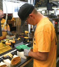 A DeWalt assembly team member uses a green Poka Yoke jig to guide screw placement as he builds a cordless drill.