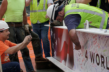 A construction worker signs the ceremonial last steel beam before it is hoisted to the top of 4 World Trade Center, Monday, June 25, 2012. The 72-floor, 977-foot tower is scheduled to open late next year.  (AP Photo/Mark Lennihan)